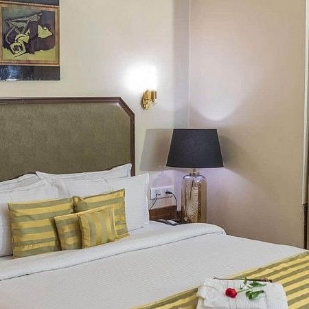 the view of a bed with yellow pillows and curtains covering the window - Hotel Polo Towers, Shillong