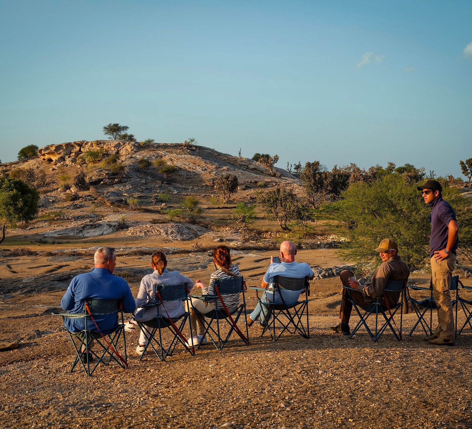 image featuring a few people sitting in a dry area probably site seeing