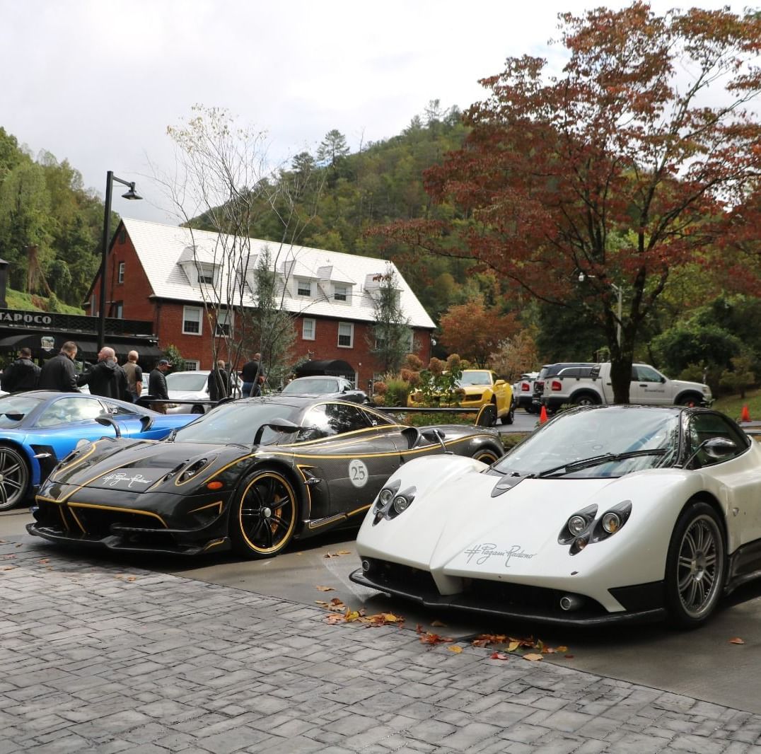 Corner view shot of several sport cars parked together at the Historic Tapoco Lodge surrounded by trees.