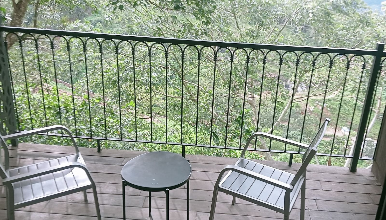 image of the balcony of the artist suite with lush green view from there with a coffee table and two chairs on the porch