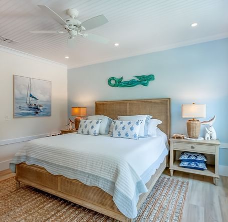 a bright bedroom with a comfortable huge bed, a bedside drawer, wall arts and a window at Abaco Inn .