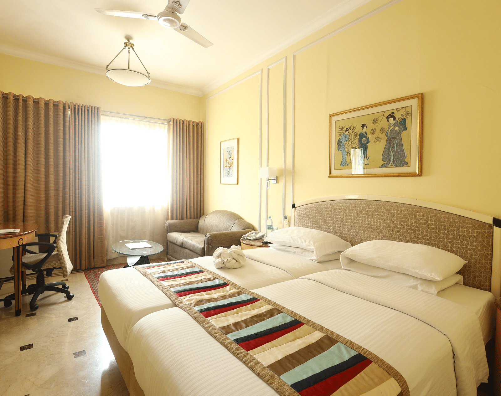 Twin beds in the Superior Room with sunlight peeking through the windows at Regency Hotel, Mumbai.