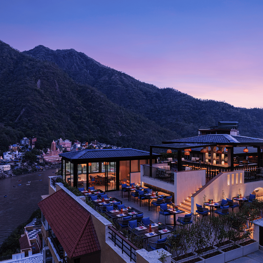 Aerial view of The Terrace at Aloha on the Ganges, Rishikesh, featuring rooftop dining, illuminated seating, and the surrounding Himalayan hills at dusk.