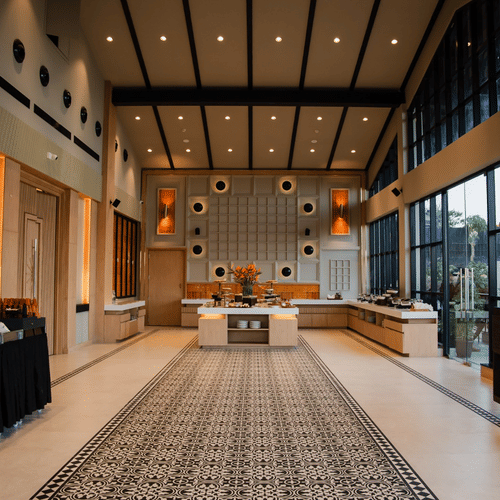 Ballroom with a high, gable-style ceiling and open layout, offering a spacious setting with comfortable sofas and a dining area for a buffet