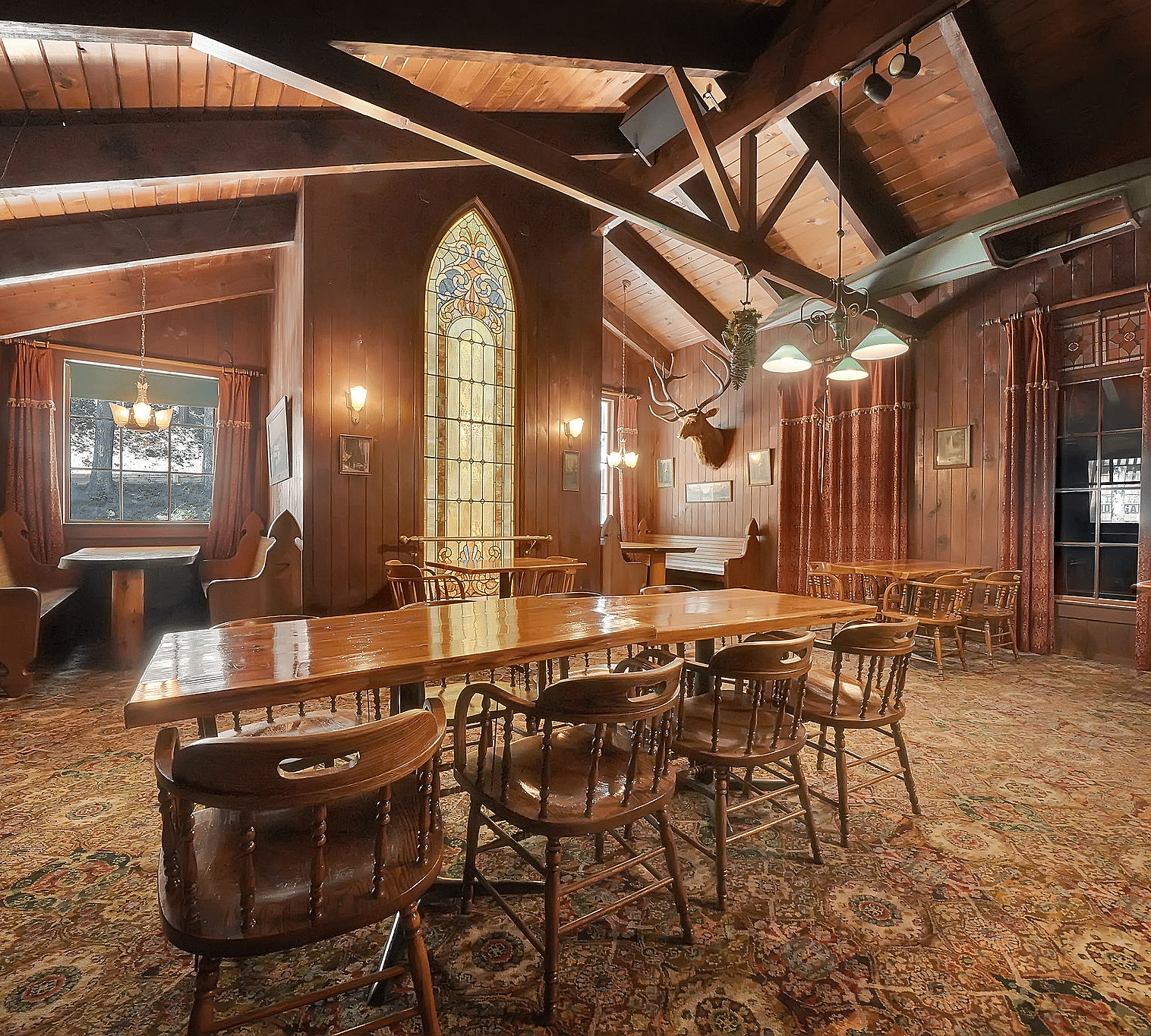 A dining arrangement in the centre of a room with a carpet and large wooden beams - Narrow Gauge Inn - A Serenite Hotel Near Fish Camp.