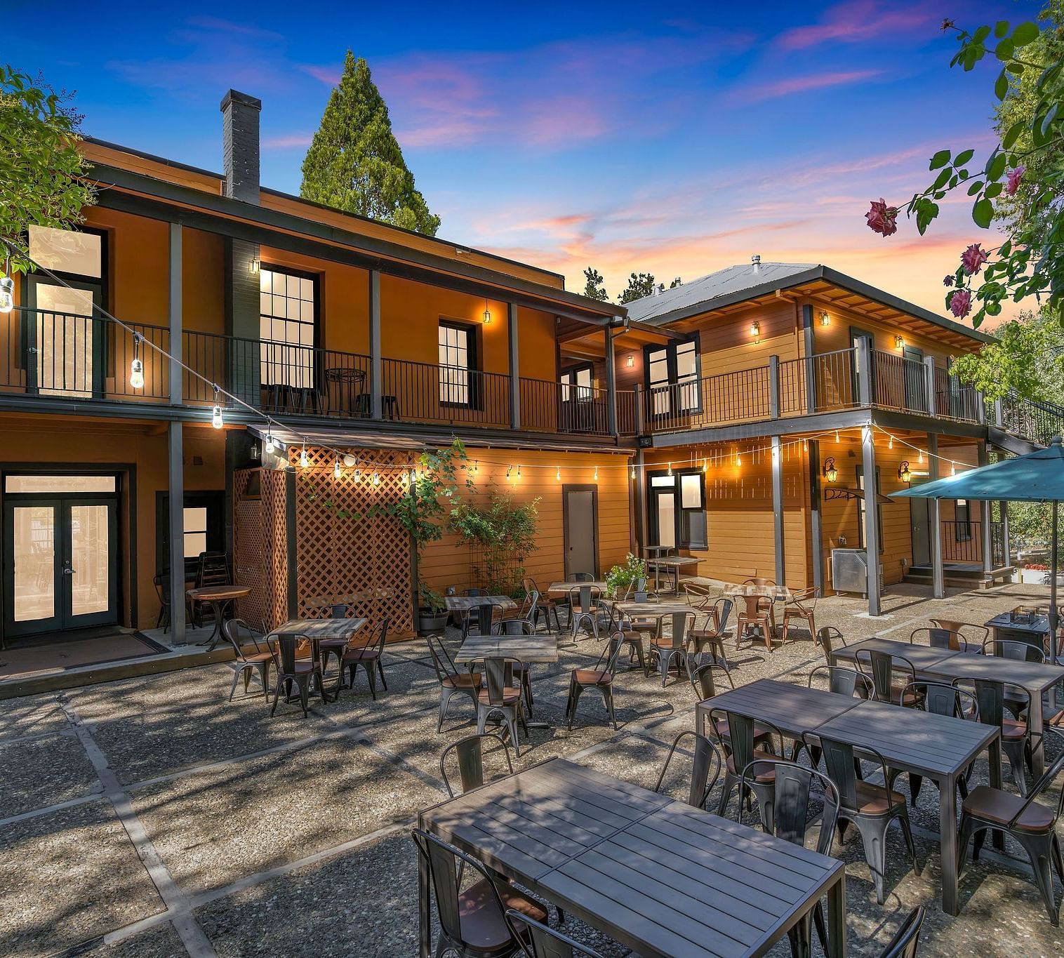 A view of the exterior of The Groveland Hotel with tables and chairs arranged in the backyard