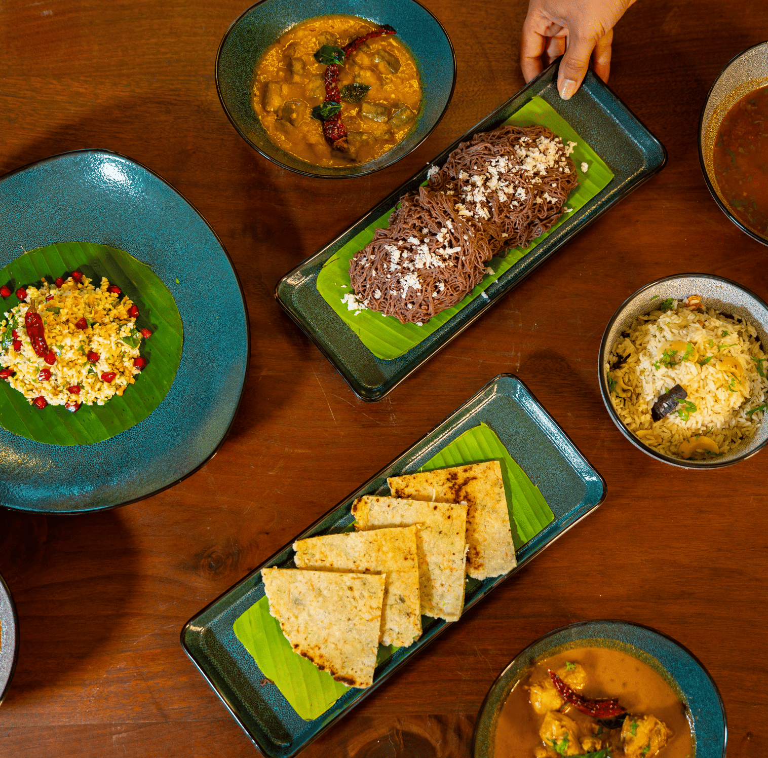 An overhead shot of a dining table at Stanley Revelation, filled with various plates of food on a wooden surface.