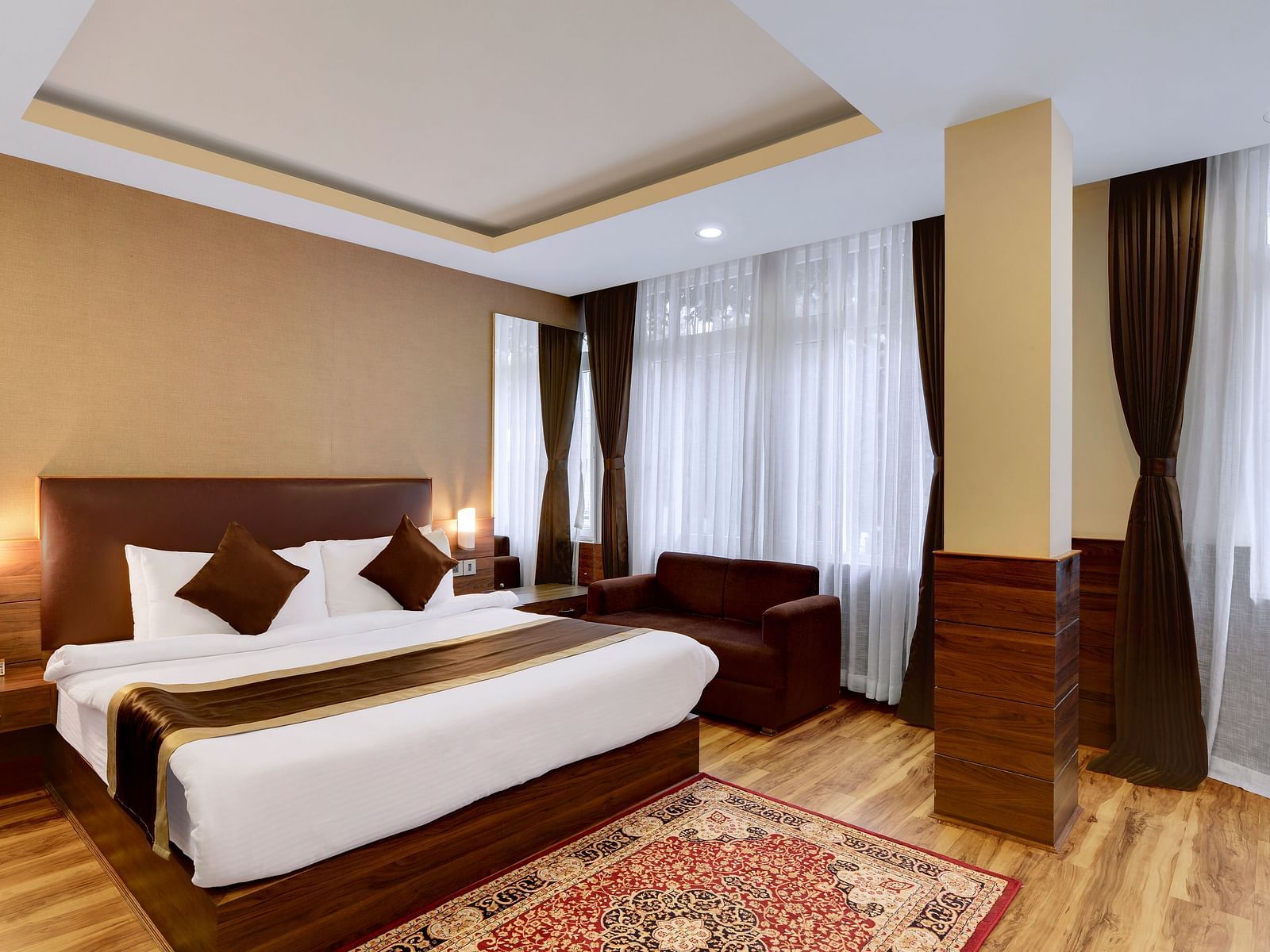 A queen bed with a sofa next to it inside Premium Room - Sumitel Shangrila, Deorali