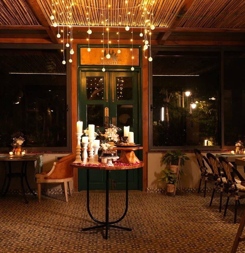 Indoor dining area at Karma Chalets with chandeliers, decorated tables, and large glass windows.