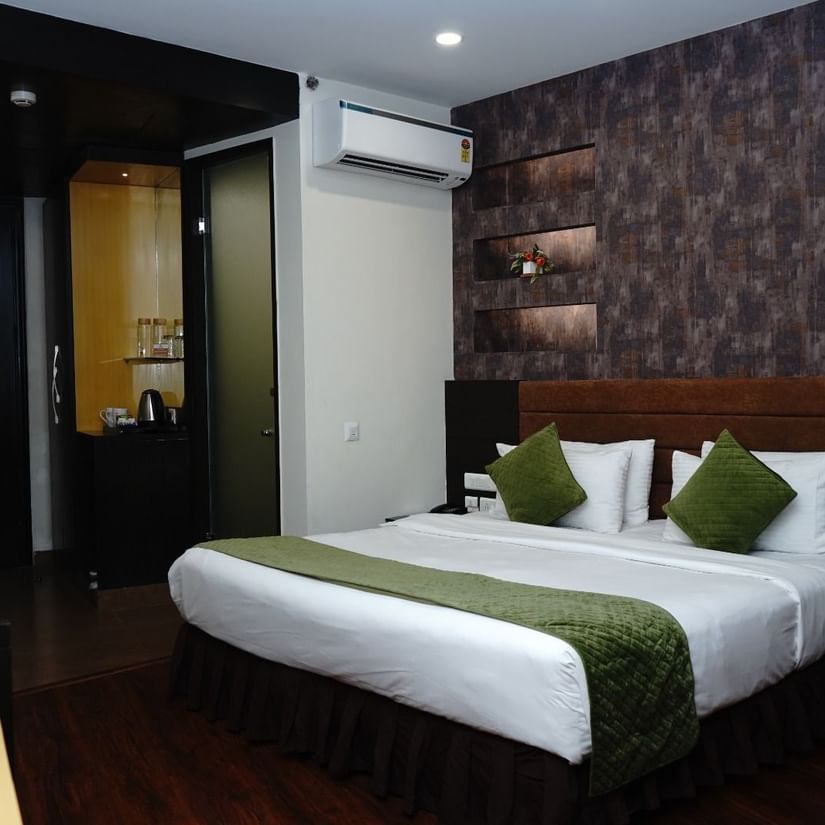 A Deluxe Room featuring a double size bed, bedside table on either side,  flat TV screen, AC, fruit basket and bouquets, and tea and coffee maker at Five Elements Hotels North Avenue, Delhi