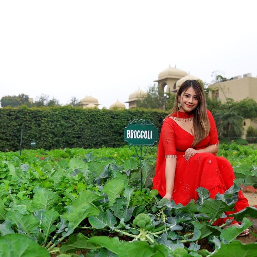 Heritage Village Manesar - a model kneeling down on the ground among numerous plants next to a signboard that reads 22broccoli 22