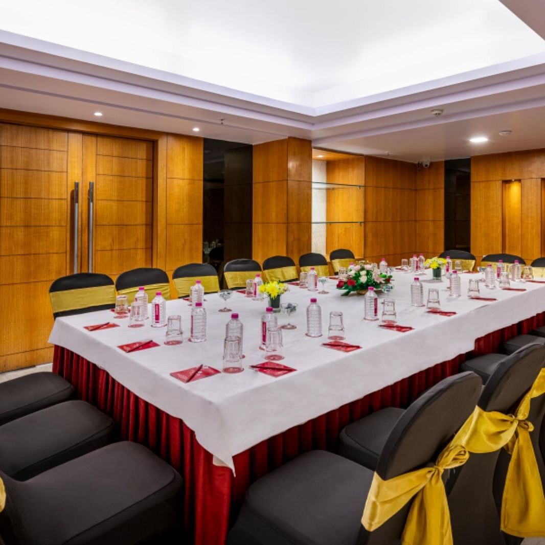 a boardroom meeting arrangement at a Banquet hall in Libra Lords Inn Jaipur with wood-panelled walls and ceiling lights
