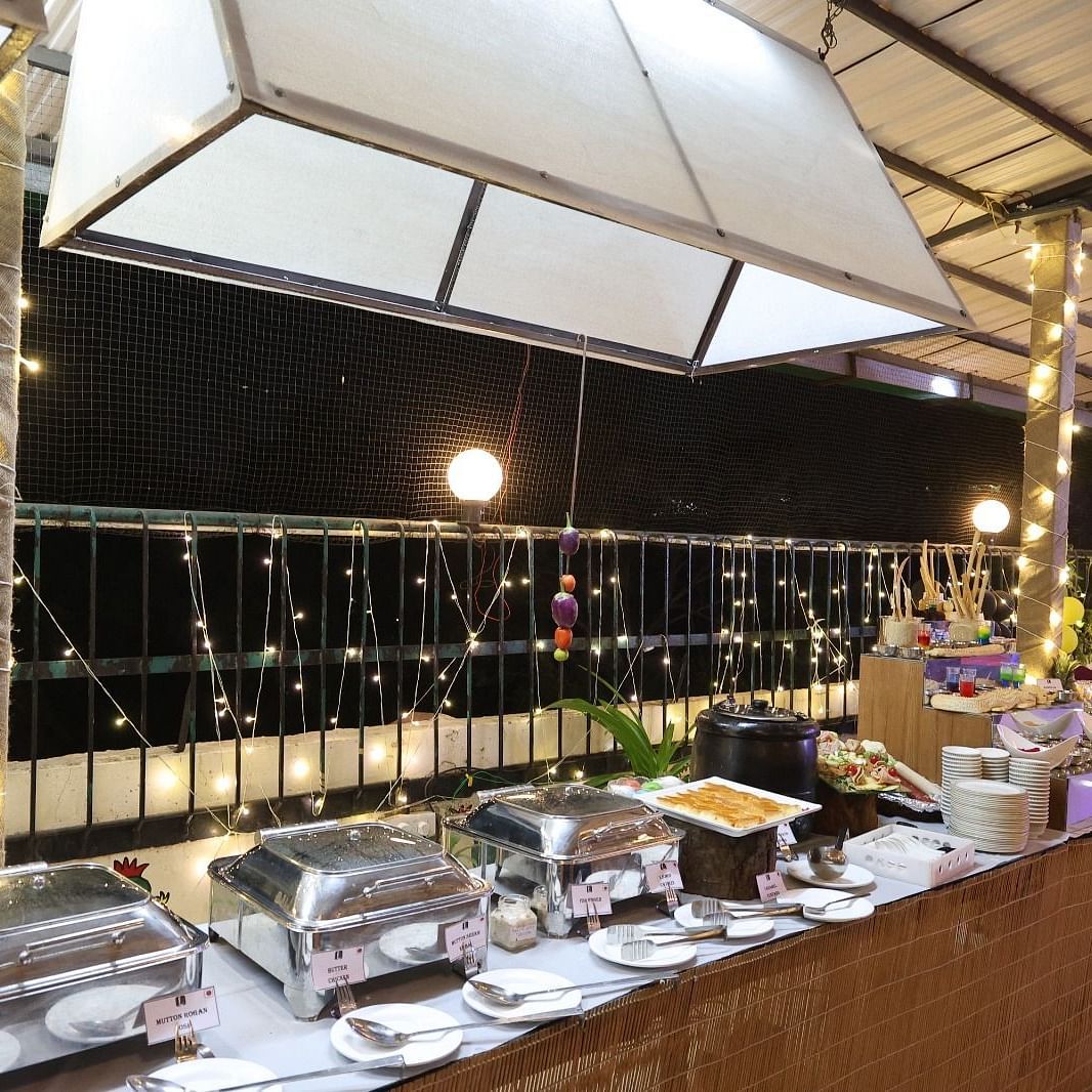 An outdoor dining area at night featuring a buffet station under illuminated canopies at Lords Inn Vadodara.