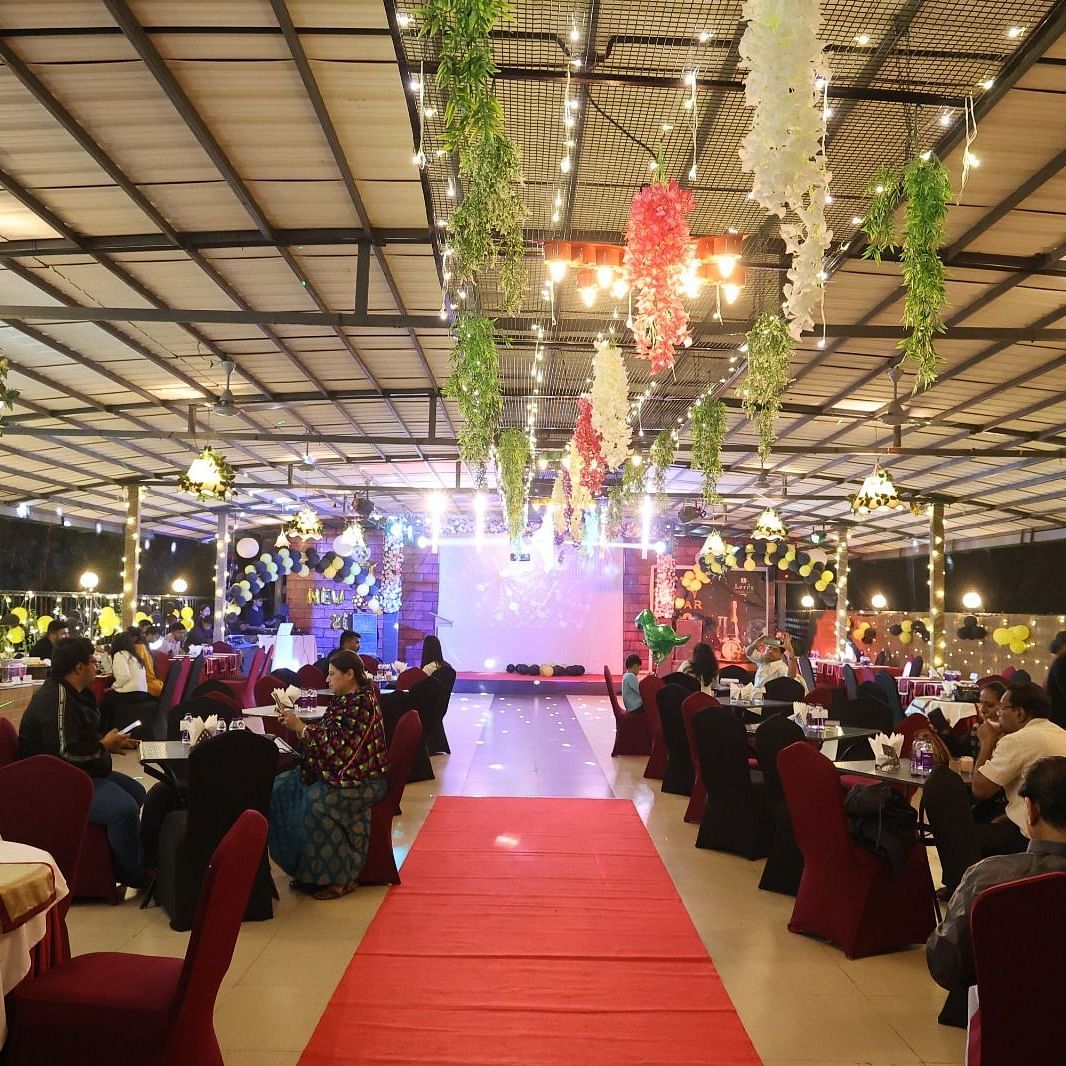An outdoor decorated dining space with a red carpet leading through seated guests at Lords Inn Vadodara.