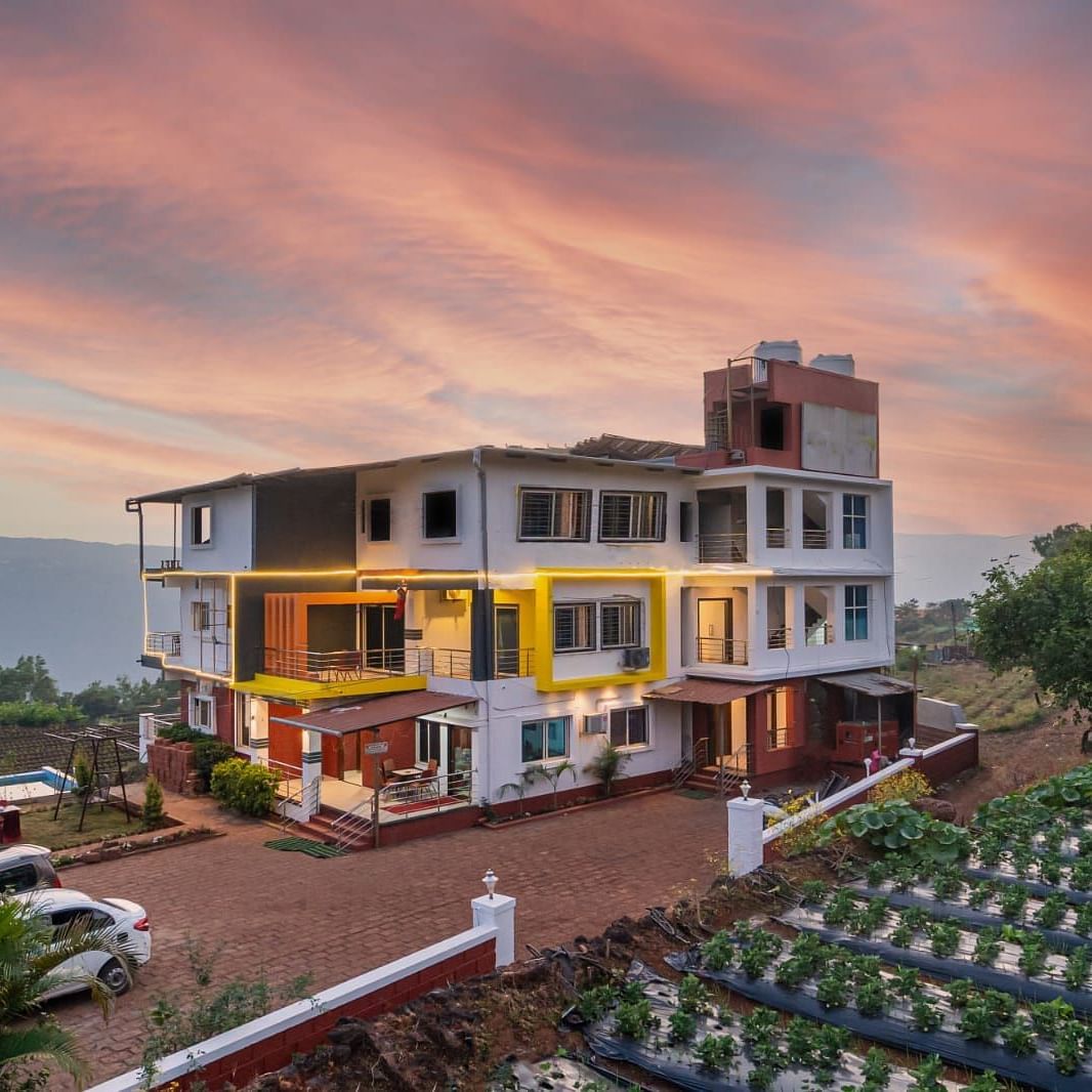 An exterior view of Strawberry King Resort, Mahabaleshwar at dusk surrounded by trees.