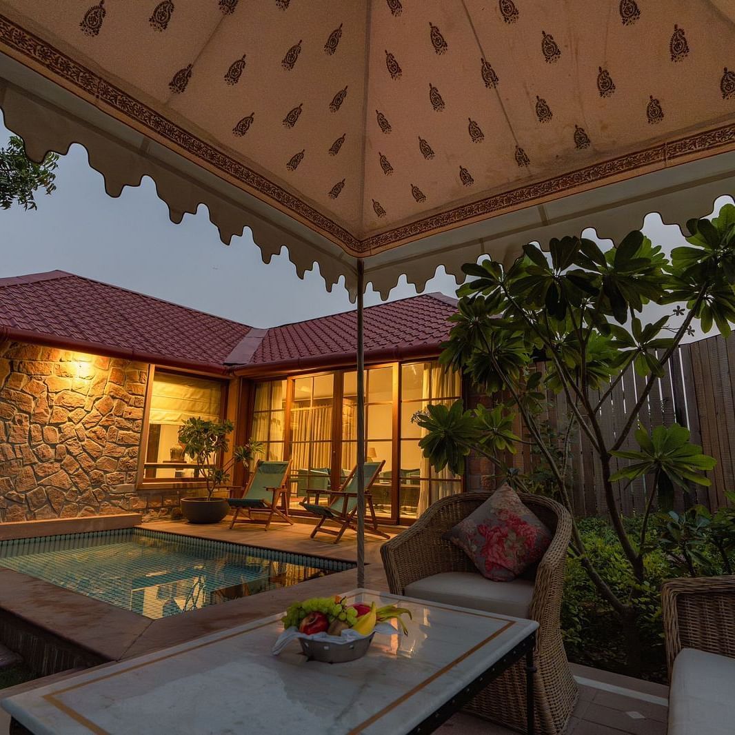 An outdoor seating area with a swimming pool in the corner at Surpura Bagh.