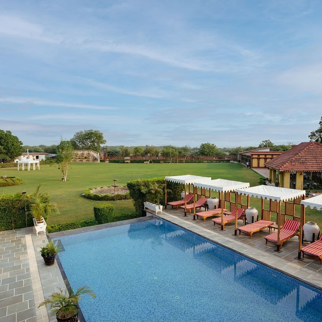 Aerial view of a swimming pool with lounge chairs on the side at Surpura Bagh.