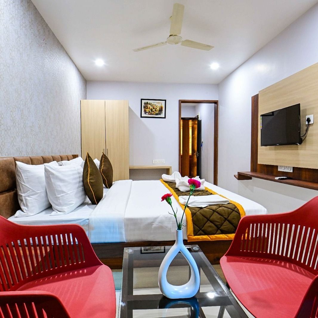 view of the  comfortable sofa setting and TV  and king size bed of Premium Balcony Room at at South Square Hotel, Bengaluru