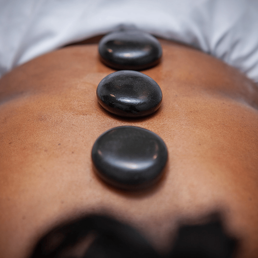 Three smooth black stones placed along a person's back during a hot stone massage