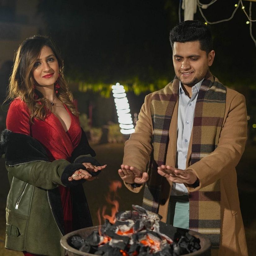Heritage Village Manesar - Image of a couple standing next to each other as they show their hands towards a grill for heat
