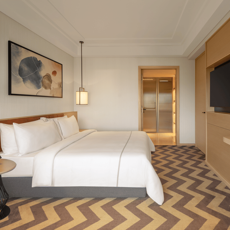 Side view of a luxurious suite room featuring a cozy bed and elegant bedside lamps at The Residency Chennai