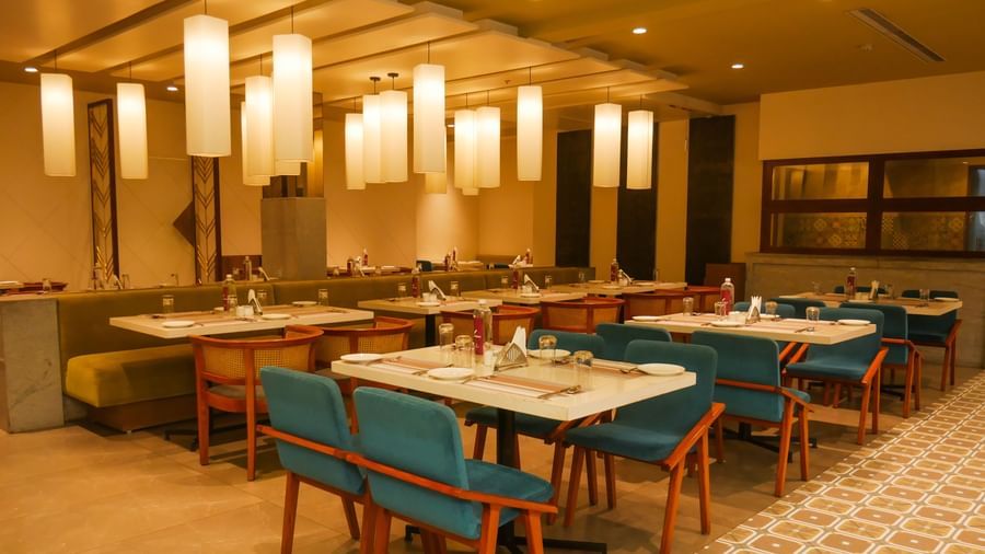 A brightly lit restaurant interior with tables set for dining and a buffet counter in the background at Shilton Dee Cee.