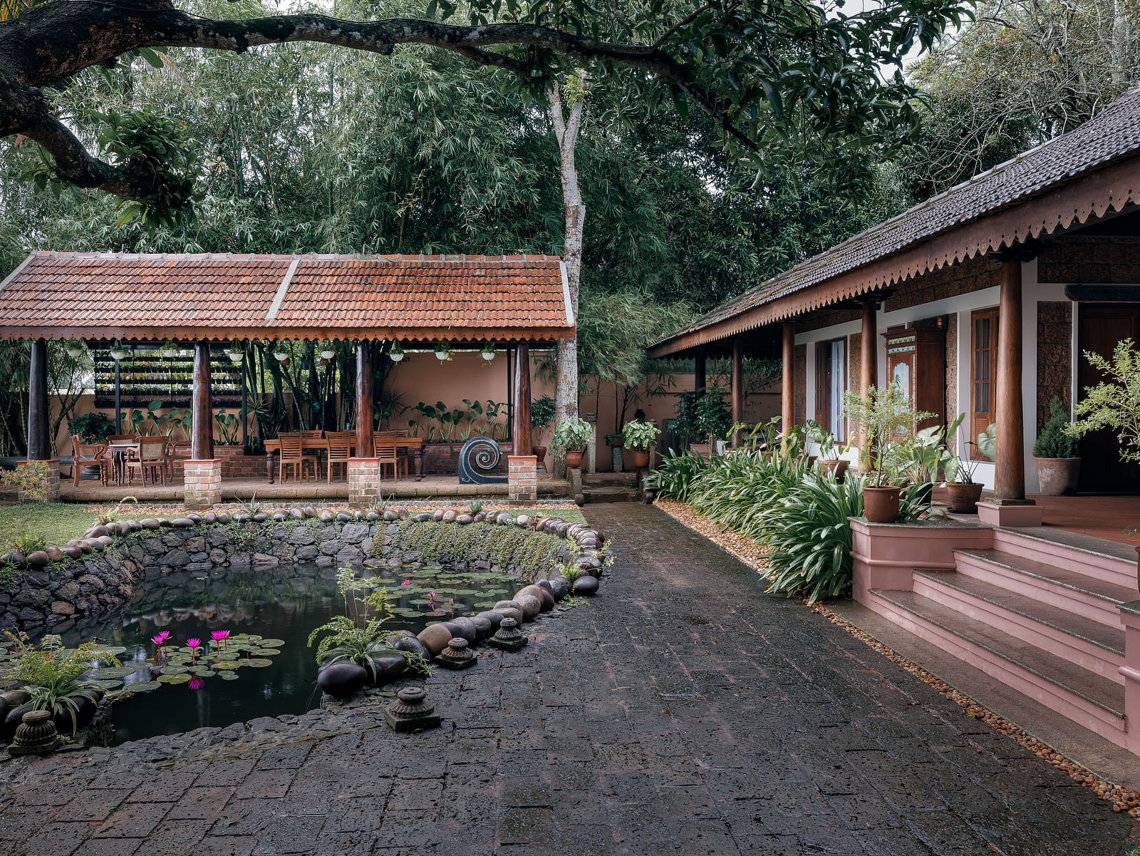 A facade of BluSalzz Villas - Muhamma Resort, Alleppey featuring the pond and the villa on the right and the restaurant in the background