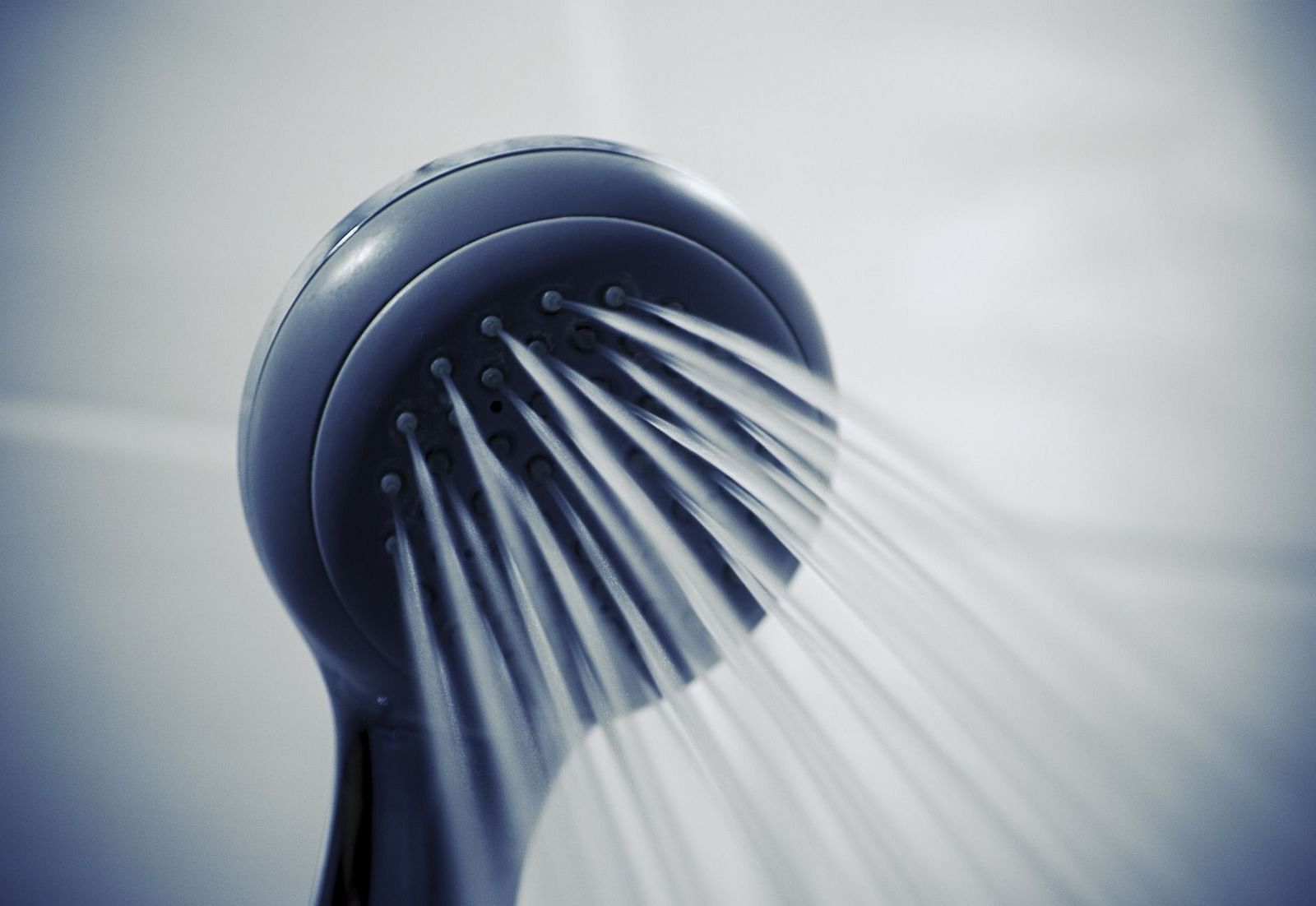 Image of a shower head with water flowing out of it.