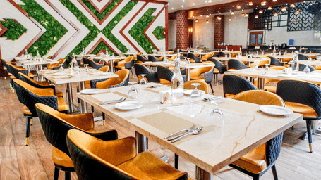 An overhead shot of the Punarvasu restaurant at Leroy Grand, Yeshwanthpur, showcasing neatly arranged dining tables with white porcelain plates and glassware.