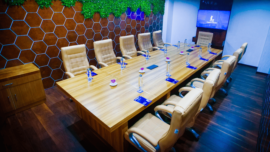 A wide-angle shot of the boardroom at Leroy Grand, Yeshwanthpur, featuring a honeycomb-patterned wall design covered with fake green moss.