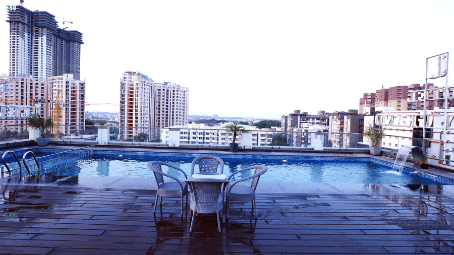 Full view of Kensho poolside rooftop pub at Leroy Grand, Yeshwanthpur, featuring a dining table on a wet pool deck overlooking the city views.