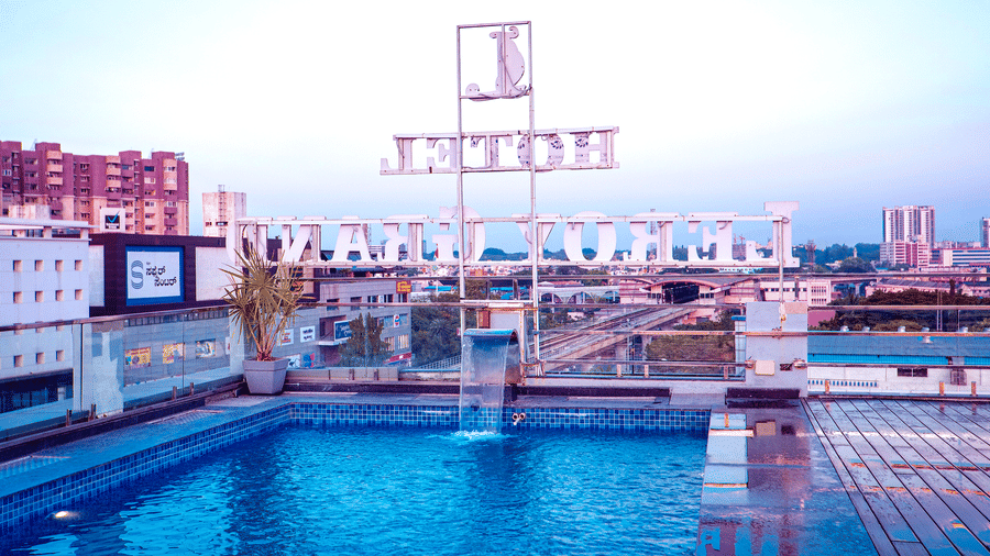 A close up of the rooftop swimming pool featuring the back side of the neon sign board of Leroy Grand, Yeshwanthpur.