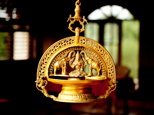 A traditional hanging oil lamp in brass, depicting Goddess Lakshmi flanked by elephants