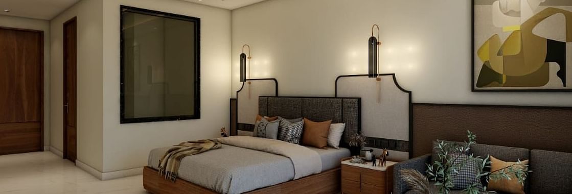 A bedroom with slightly low lighting featuring a double bed with an artistic head board along with a common seating area besides it. - Namaste Corbett