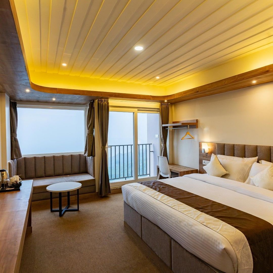 An image of a bedroom with ceiling lights, flat TV screen, a seating area and a balcony - Avianna Group of Hotels & Resorts