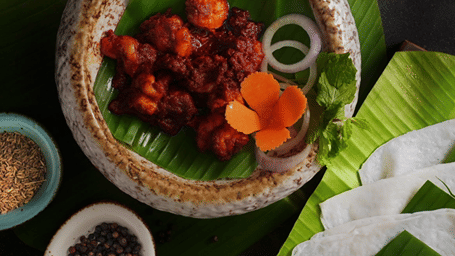 Kebabs plated with a garnish on a leaf, served with small bowls, at Goldfinch Hotels & Resorts.