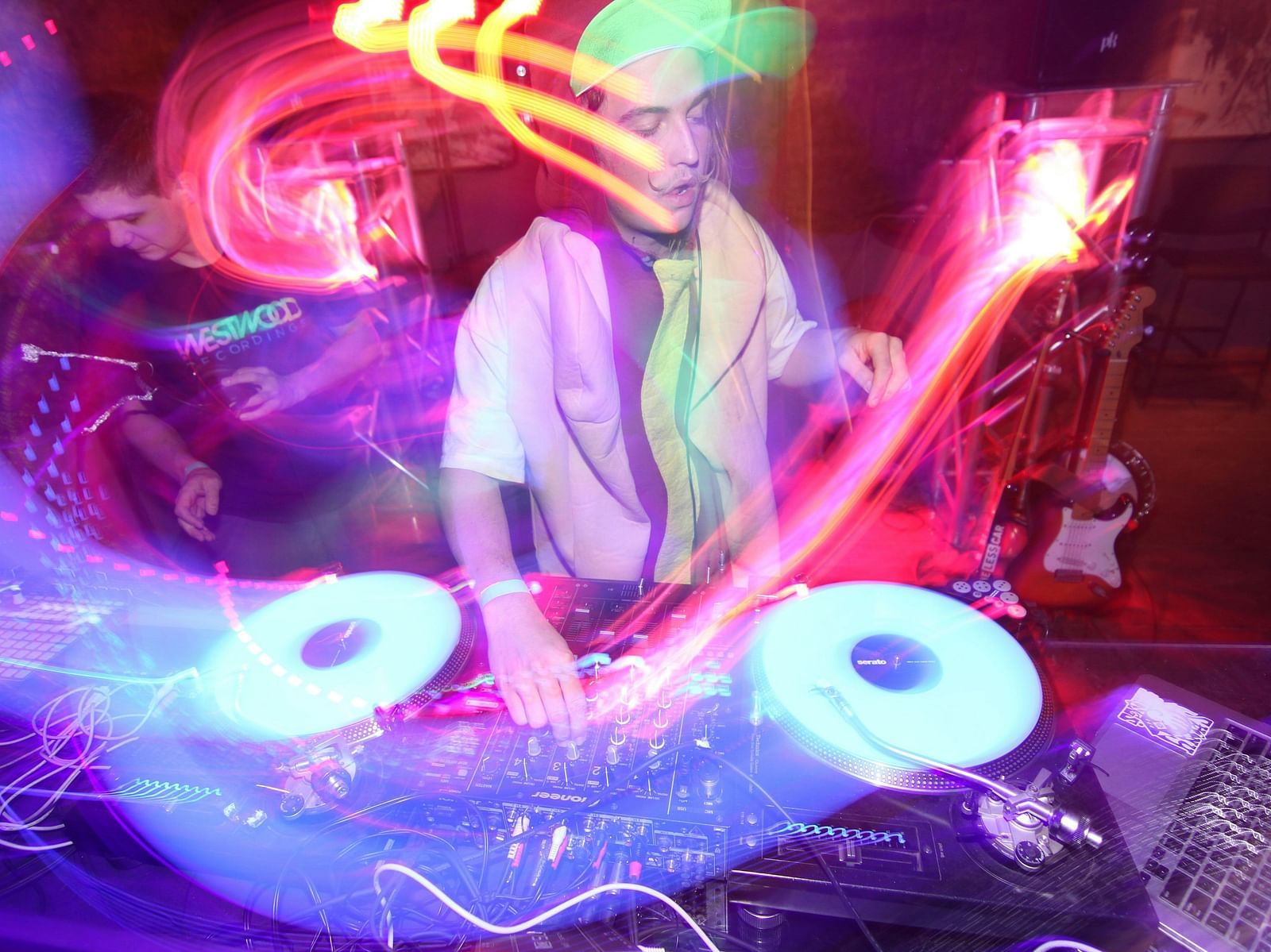 A psychedelic picture with neon overlays of a DJ playing music on his turntable