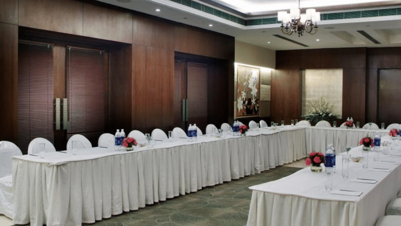U-shaped conference seating arrangement with long white-clothed tables and white chairs at Goldfinch Bengaluru.