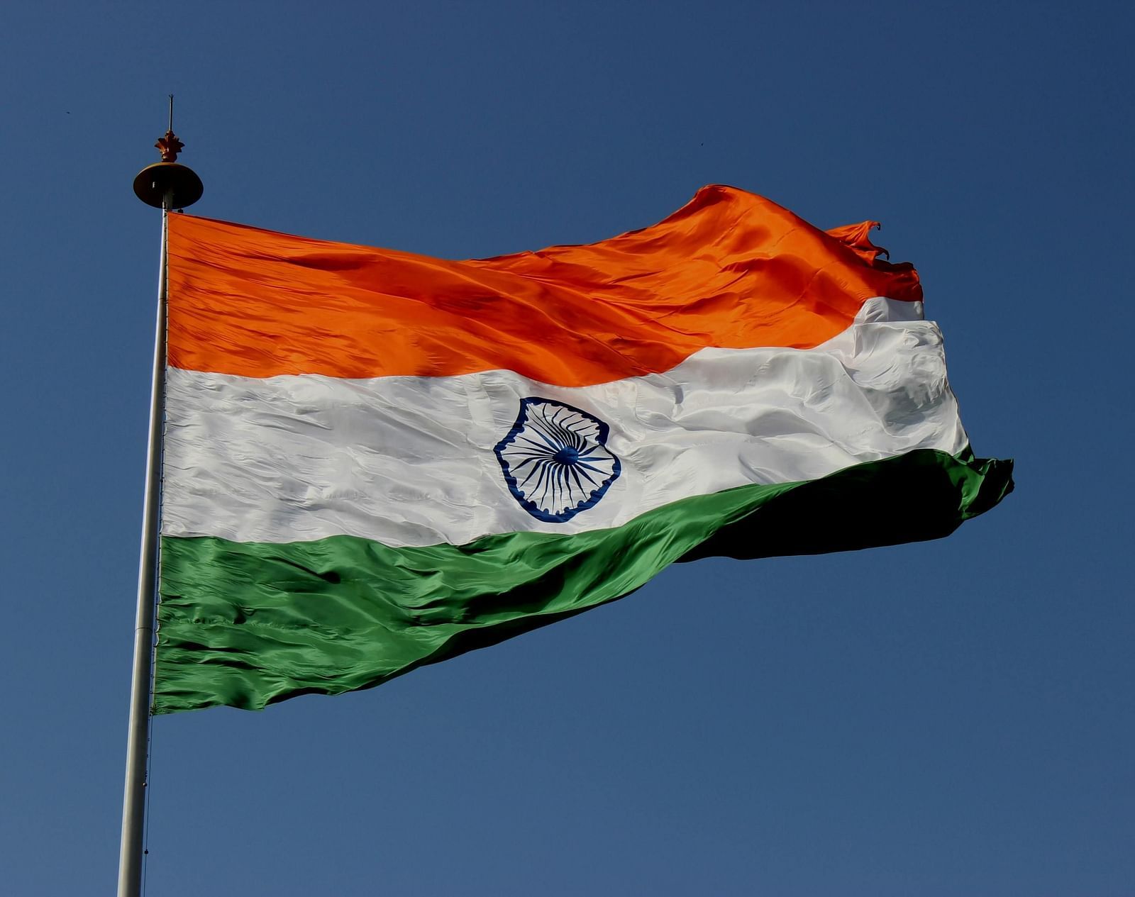 A close up shot of the Indian National Flag fluttering in the sky.