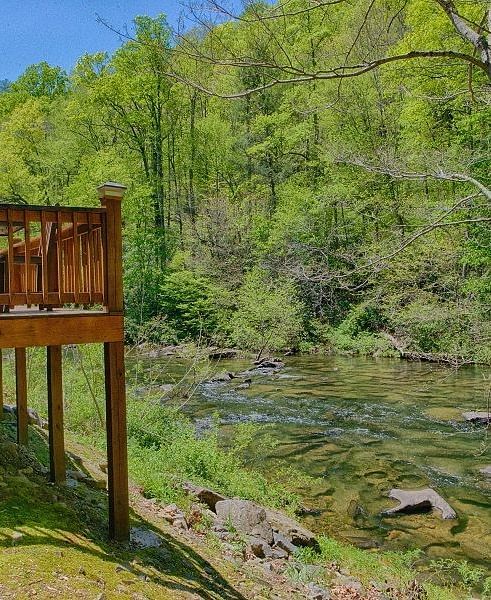 a wooden porch overlooking the Cheoah river and the surrounding greenery - Historic Tapoco Lodge