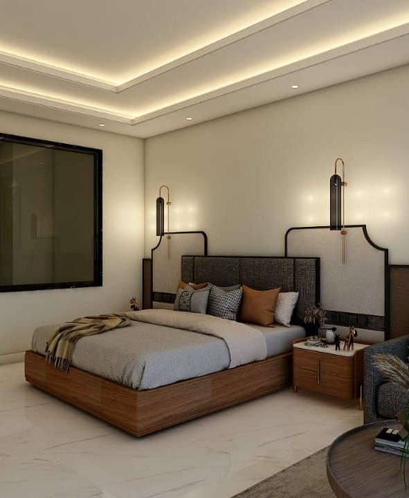 A bedroom with slightly low lighting featuring a double bed with an artistic head board along with a common seating area besides it. - Namaste Corbett