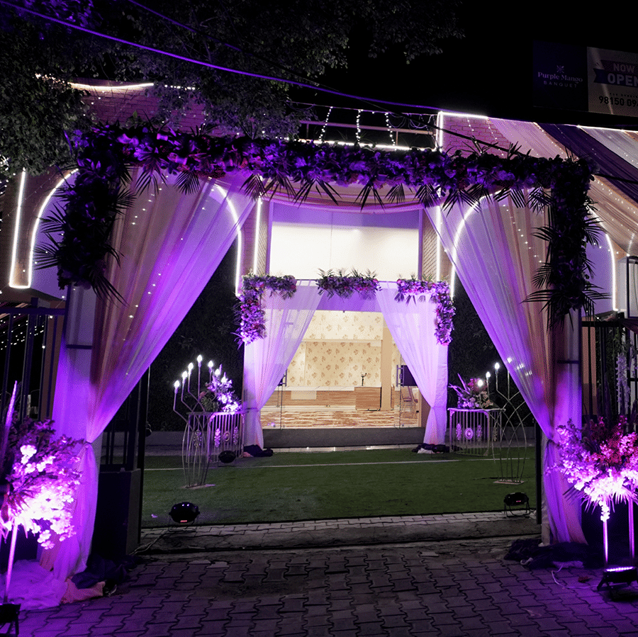 Decorative entrance archway illuminated with purple lighting at night at Mango Grove Hotel.