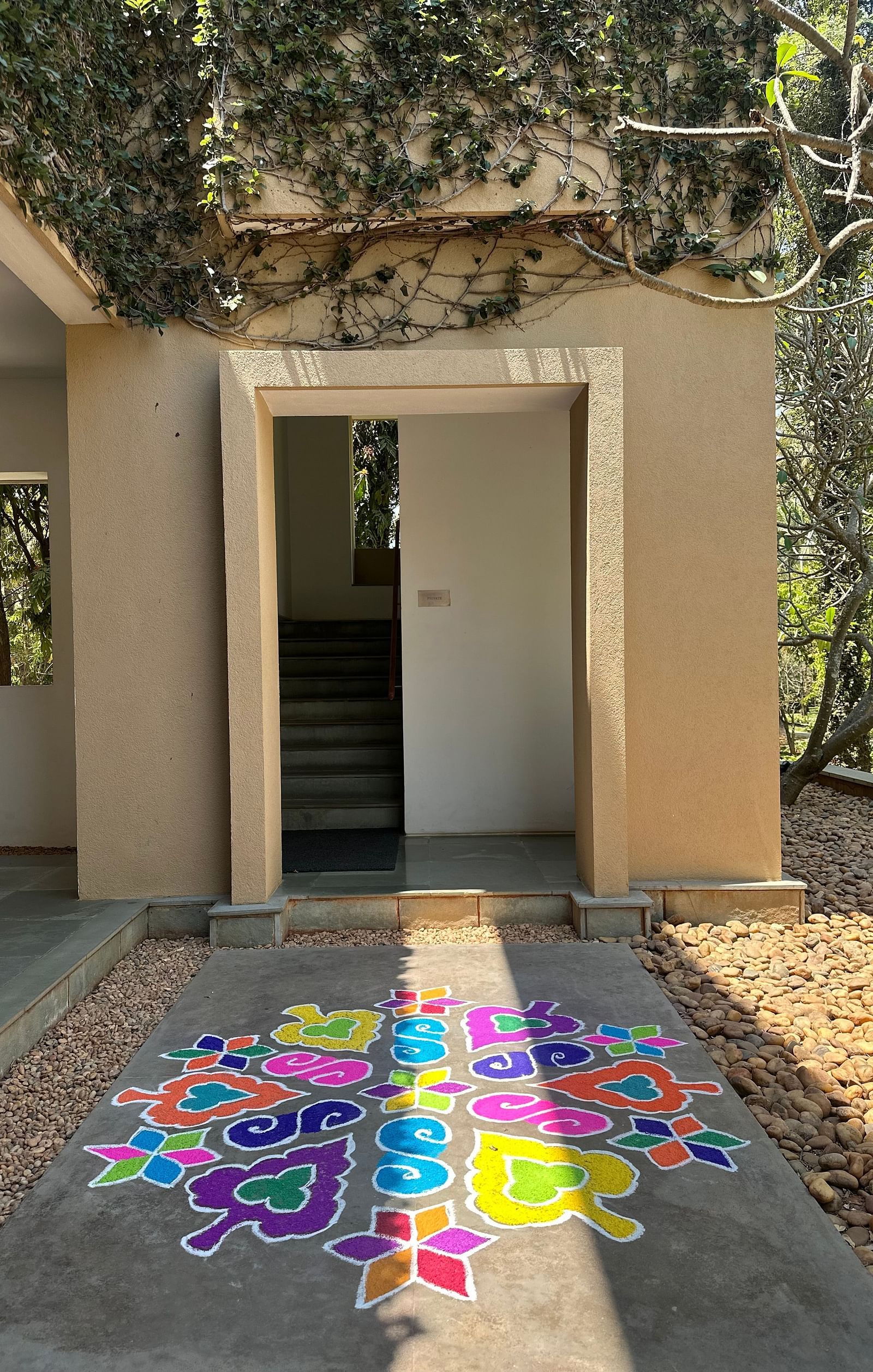 Open white door leading to garden path with colorful paint splatters, outdoor entrance, sunny day - Shreyas Retreat