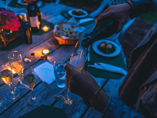 A night time shot of a woman pouring champagne in to a glass 