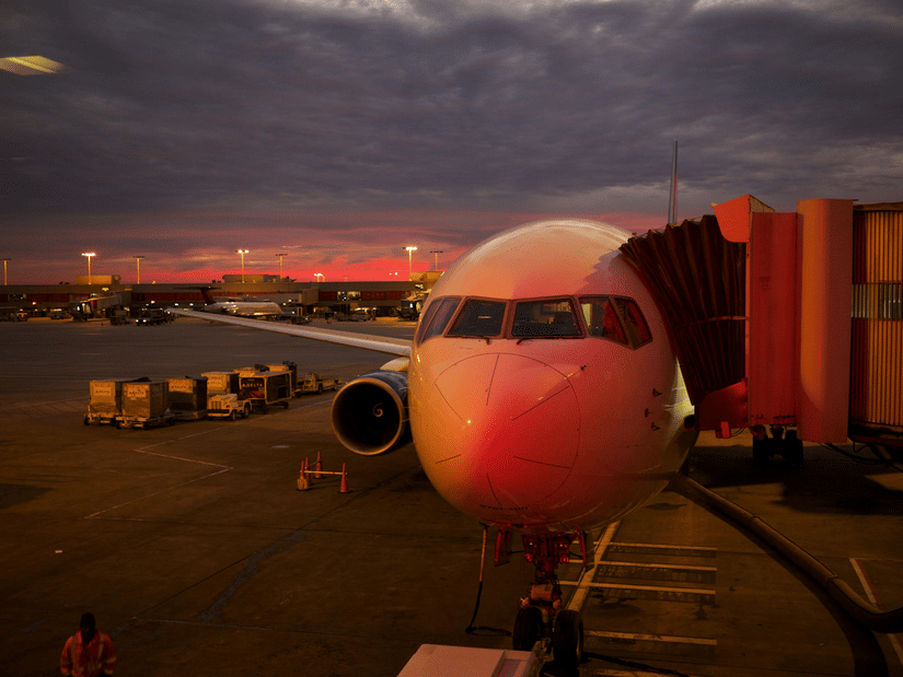 A close up shot of an aircraft during a late evening with the aerobridge attached.