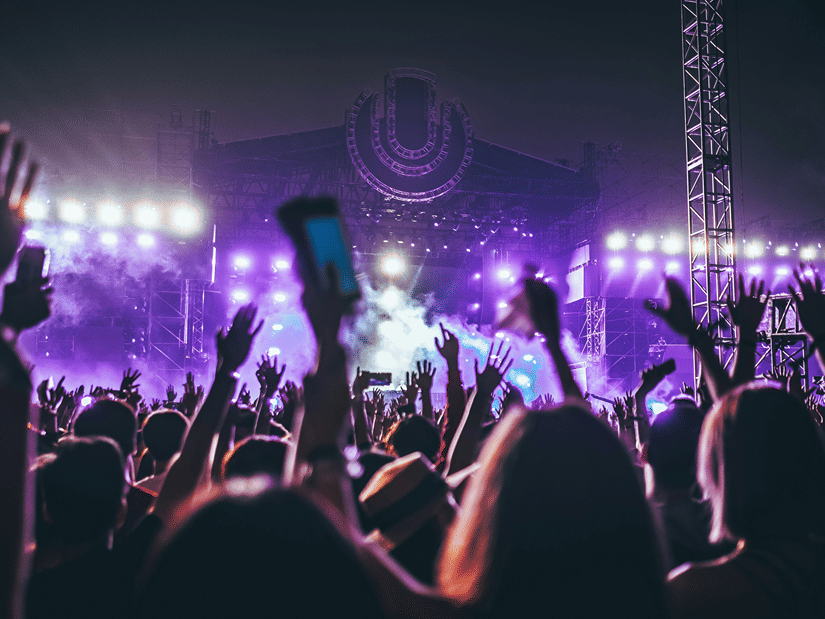 concertgoers with their hands in the air as lights shine on them