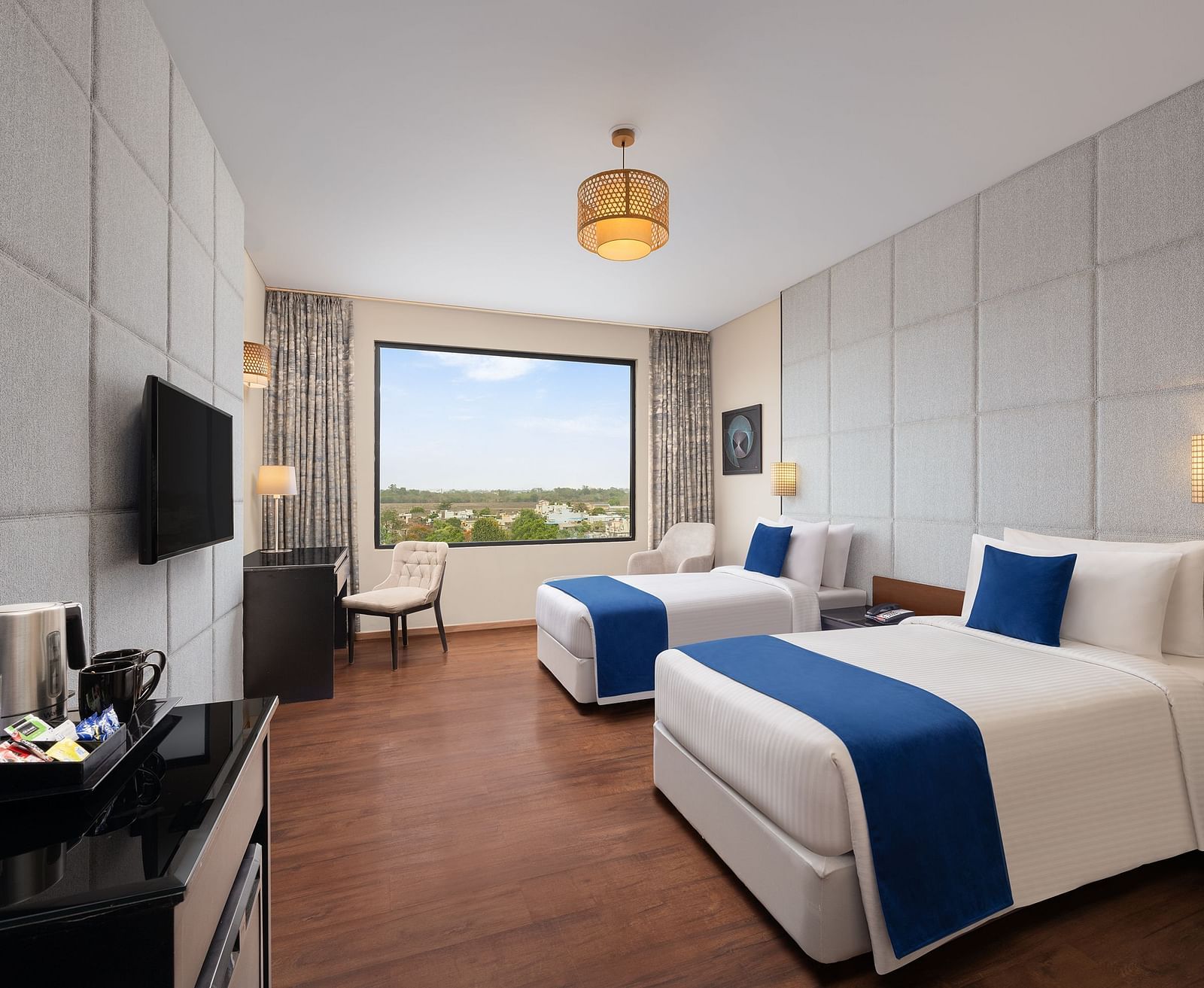 Deluxe Twin Room at Essentia Luxury Hotel, Indore with twin beds, a television and a work desk and chair
