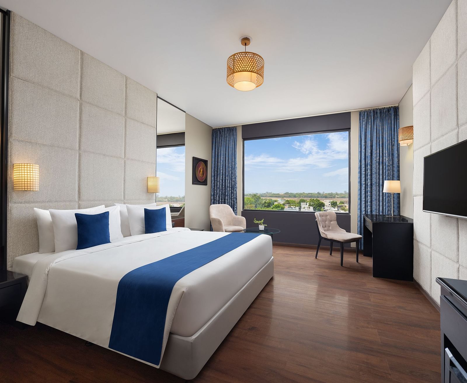 Deluxe king room at Essentia Luxury Hotel, Indore with a double bed and a television