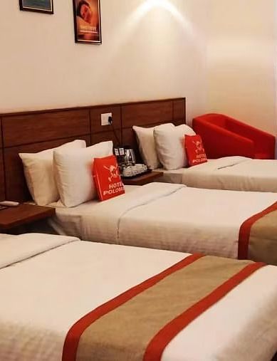 View of three beds arranged in Max Club Room with photo frames mounted on the wall in the background - Max Hotel Prayagraj.