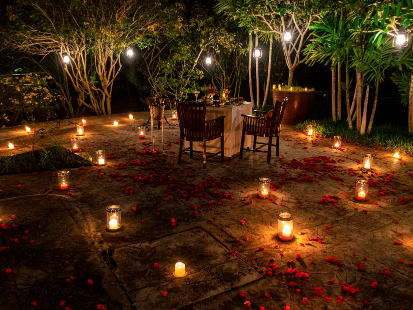 An overview of a candlelight dinner with a table set for 2 in the centre and candles spread across at The Serai Chikmagalur.